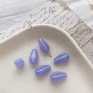 Close-up of purple teardrop Czech glass beads with blue stripes for DIY jewelry making
