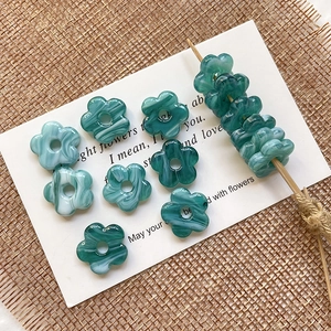 Detailed macro of blue marble patterned floral glass beads on a wooden pick for DIY crafts