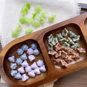 Detailed view of colorful trumpet flower glass beads in a wooden tray for DIY jewelry