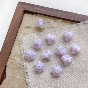Macro shot of purple striped morning glory glass beads and metal pin on linen fabric