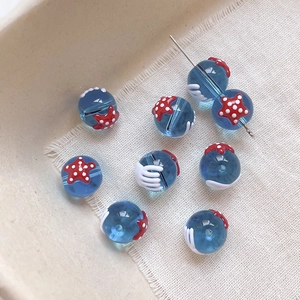 Gros plan de perles en verre bleu avec motif d'étoile de mer rouge pour bijoux DIY