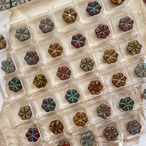 Vue à plat de perles de verre tchèque en forme de fleur dans des boîtes de rangement carrées