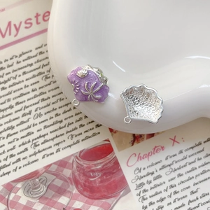 Détail macro du pendentif coquille en émail violet avec relief de palmier et soleil
