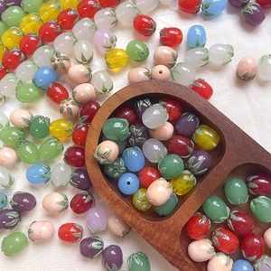 Macro detail of colorful glazed glass beads in eggplant and berry shapes for DIY crafts