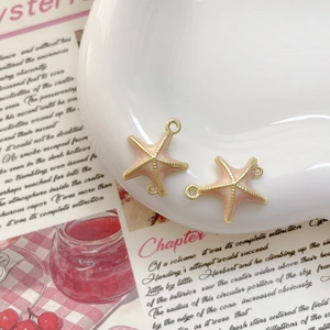 Détail de breloques étoiles de mer roses et dorées sur plateau pour bijoux DIY