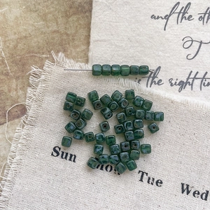 Macro view of vintage dark green glass cube beads with Picasso texture for DIY jewelry