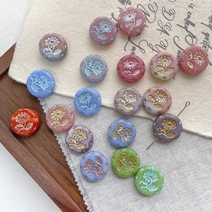 Detailed macro view of colorful Czech glass beads with embossed daisy floral patterns