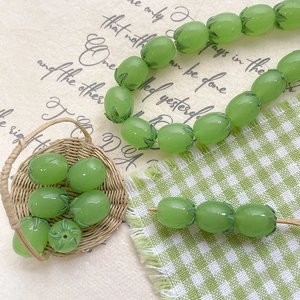 Translucent green grape glass beads for DIY jewelry making in a decorative basket