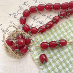 Macro shot of glass tomato beads with green leaves in a mini basket for DIY jewelry making