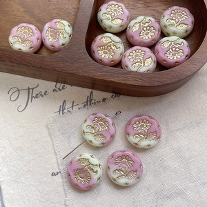 Macro view of pink and beige Czech glass beads with golden embossed sunflower details