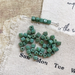 Macro detail of Morandi green Czech glass cube beads for DIY handmade jewelry crafting