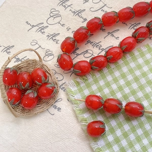 Macro shot of glass tomato beads for DIY jewelry making in a tiny woven basket