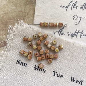 Macro shot of square Picasso glass beads with vintage brown marble swirls for DIY crafts