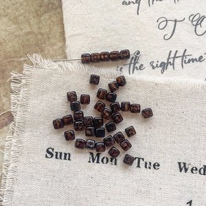 Macro shot of vintage amber Czech glass square beads on a metal pin for DIY jewelry