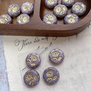 Detailed macro view of lilac glass sunflower beads with gold floral engravings for DIY