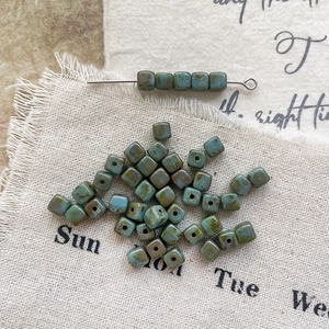 Macro detail of Picasso-style teal square Czech glass beads for DIY jewelry making