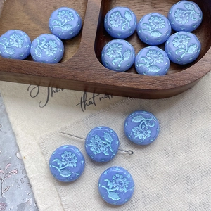 Macro shot of blue Czech glass beads with vintage flower relief and pearlescent finish