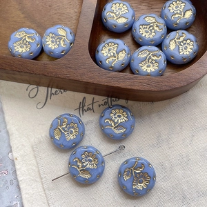 Macro shot of vintage blue glass beads with gold sunflower patterns for jewelry making