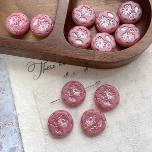 Macro shot of pink Czech glass daisy beads with detailed relief patterns on a wooden tray
