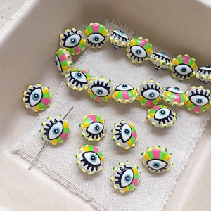 Macro detail of colorful evil eye glass beads for DIY jewelry making on white textured fabric