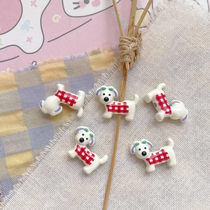 Macro detail of five cute resin puppy charms with red checkered patterns for DIY jewelry