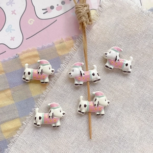 Detail of five cute cartoon Dalmatian dog beads with pink hats for DIY bracelet making