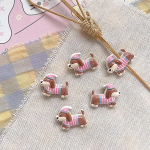 Close-up of cute resin dog charms with striped hats for DIY jewelry making