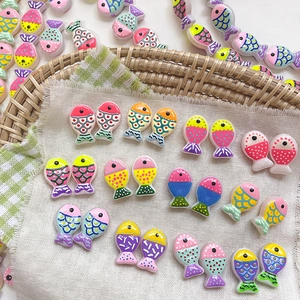 Detailed close-up of colorful dotted fish-shaped resin beads for DIY jewelry making