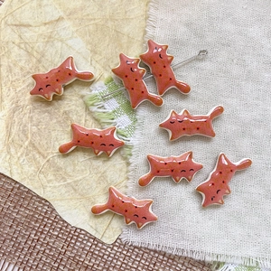 Dettaglio di 7 ciondoli a forma di gatto in ceramica rosso mattone per creazione gioielli