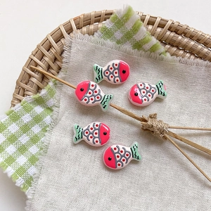 Macro detail of five colorful fish-shaped resin beads for DIY jewelry making