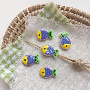 Detail of colorful resin fish beads for DIY jewelry making on a creative tray display