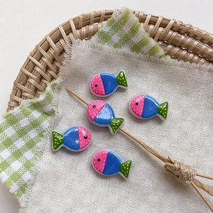 Detailed view of handmade colorful glass fish beads with polka dots in a wicker basket