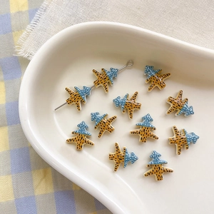 Macro detail of Christmas tree shaped alloy beads with blue and yellow striped enamel