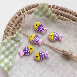Detail of five colorful resin cartoon fish beads for DIY handmade jewelry crafting