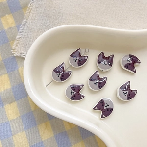 Macro shot of cartoon cat-shaped ceramic beads with purple color-blocking for DIY crafts