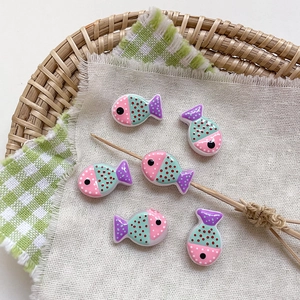 Close-up of handmade glass fish beads with colorful polka dots for DIY jewelry making
