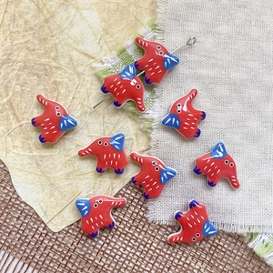 Primo piano di perline a forma di elefante in ceramica rossa con orecchie blu per gioielli