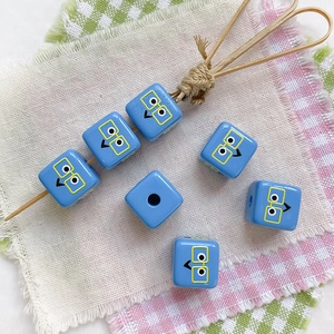 Macro detail of blue square character beads with cartoon faces for DIY jewelry making
