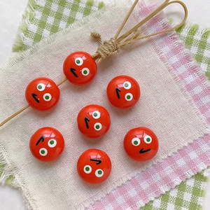 Macro shot of glossy red round acrylic beads with cartoon facial expressions for DIY craft