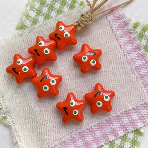 Close-up of orange star-shaped acrylic beads with funny expressions for DIY jewelry crafts