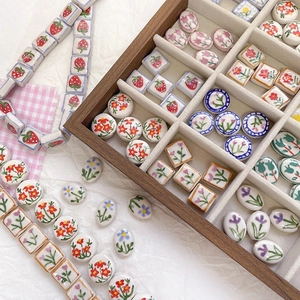 Detalle de cuentas de cerámica pintadas a mano con fresas y flores en caja de madera