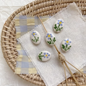 Detalle macro de cuentas ovaladas de cerámica pintadas a mano con motivos florales azules DIY