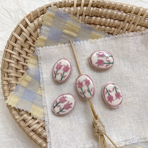Detalle macro de cuentas de cerámica ovaladas con motivos de tulipanes rosas para joyería