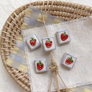 Detalle de cuentas cuadradas de cerámica con fresas y bordes azules para bisutería DIY