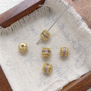 Primer plano de cuentas cilíndricas de oro de 18k con circón púrpura para joyería artesanal