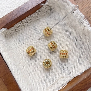 Detalle macro de cuentas espaciadoras bañadas en oro 18k con circonitas ámbar y calados