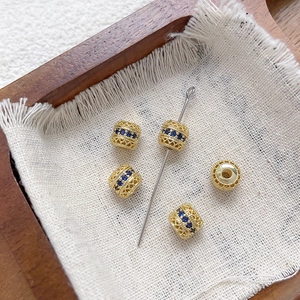 Primer plano de cuentas de filigrana bañadas en oro de 18k con circonitas azules.