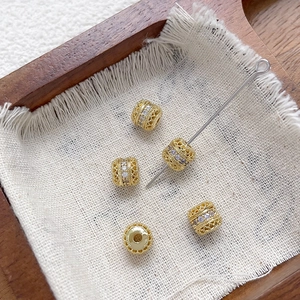 Detalle de cuentas espaciadoras caladas bañadas en oro de 18k con circonitas brillantes