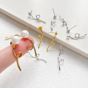 Asymmetric spiral pearl drop earrings in gold and silver finish shown on fingers