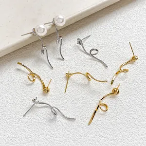 Detailed view of gold and silver curved streamline earring studs with white pearl accents